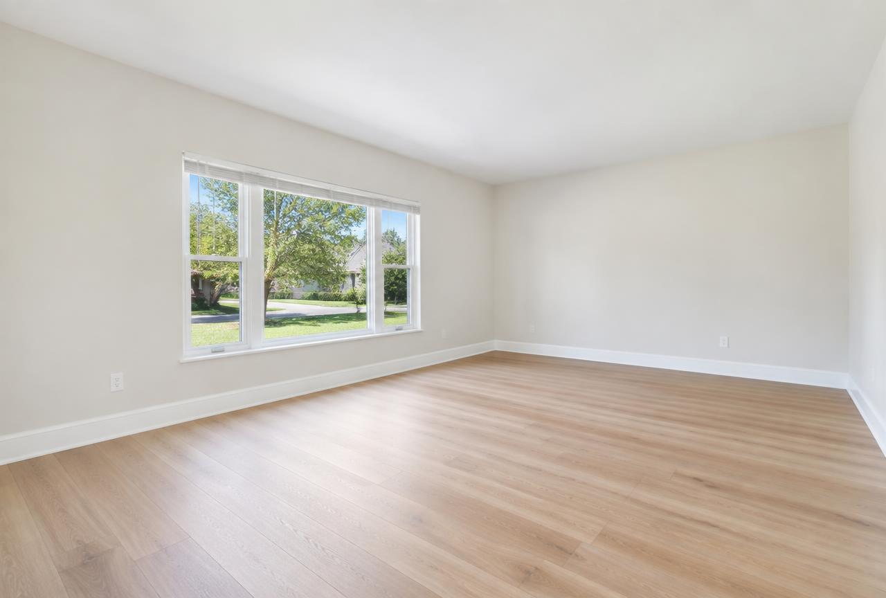 The same living room with new light oak luxury vinyl plank flooring and clean white baseboards.